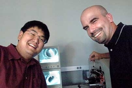 Paul Huang, graduate student in biological engineering, left, and Professor Forest White of biological engineering with a mass spectrometer showing the electrospray ionization tip of a liquid chromatography column.  Samples are loaded on the column and electrosprayed into the mass spectrometer, where their mass and sequence is identified, allowing White and Huang to analyze the sample.