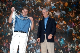 Charles M. Vest prepares to tie a juggler's hand behind his back as part of a demonstration of one-armed juggling at Vest's farewell party on Sept. 18, 2004.