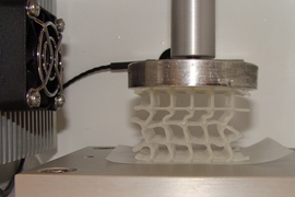 A 3D-printed soft, flexible scaffold that is coated in wax and is being compressed in a temperature-controlled chamber. Heating a composite whose wax coating has broken can enable the wax to soften and "heal" to restore its original strength and properties.
