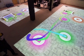 Researchers are using a small group of robotic helicopters to address the problem of drone package delivery. The scenario includes base stations (marked with a "B") and destinations (marked with a "D"). The colored lines represent the planned paths of the 4 helicopters.