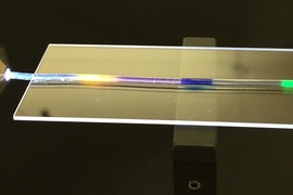 MIT researchers have developed a stretchy optical fiber in which they have injected multiple organic dyes (yellow, blue, and green regions). In addition to lighting up, the dyes act as a strain sensor, enabling researchers to quantify where and by how much a fiber has been stretched. 
