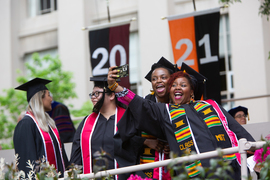 Students in caps and gowns pose for a selfie.