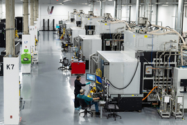 A giant digital product machine with a few people working on computers near it.