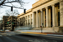 Long-exposed photo of Mass Ave and Building 7 steps, with streaks of car lights and blurred cars.