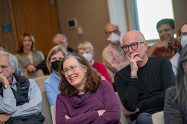 Members of the audience watch the speech, some smiling and some wearing face masks.