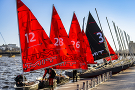 About 6 red-sail boats on the dock, with one couple getting ready to push off.