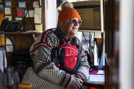 Charles wears a life jacket while indoors, looking out a window.