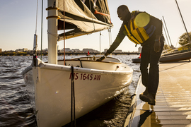 A community member on the dock gently pushes their boat towards them.