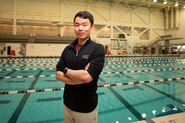 Lu stands with his arms crossed, with the Z Center pool in background.