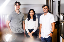 Angel Bu, Ritu Raman, and Brandon Rios stand in the lab, with blurry light in foreground.