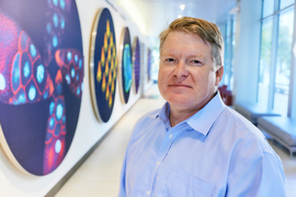 Darrell Irvine stands near circular paintings inside the Koch Institute building.