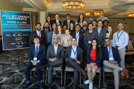 About 30 participants pose for a group photo next to a sign that says, “2024 MIT Energy Conference; Short and Long: A Balanced Approach to the Energy Transition.”