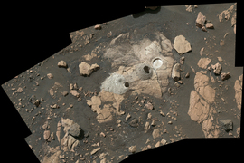 Aerial view shows the brown and tan landscape of Mars. Circular holes show where the rover extracted samples.