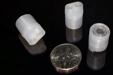 Three 3D-printed pumps next to a dime for size comparison