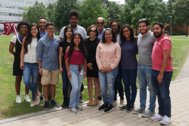 Photo of 14 people posing together in MIT's Hockfield Court on a summer day