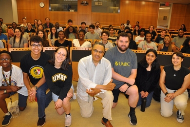 Photo of people in a crowded auditorium, with the front row kneeling